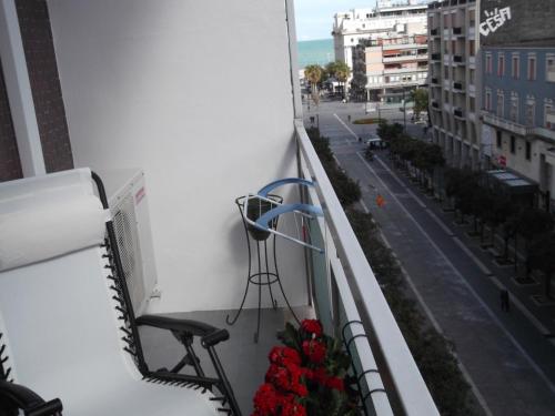 a balcony with a chair and flowers on a city street at La Dimora del Conte in Pescara