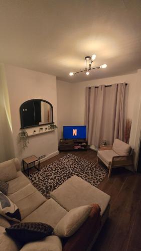 a living room with a couch and a tv at Cosy 3 Bedroom, 5 Bed House! in Headingley