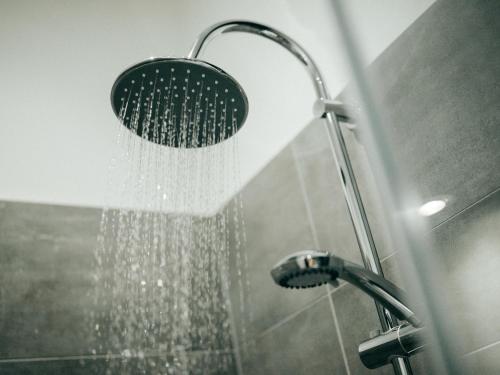 a shower with a shower head in a bathroom at JustStay Mülheim Hotel & Apartments in Mülheim an der Ruhr