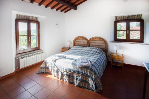 a bedroom with a bed and two windows at Tenuta di Paganico - I Roggeti in Paganico