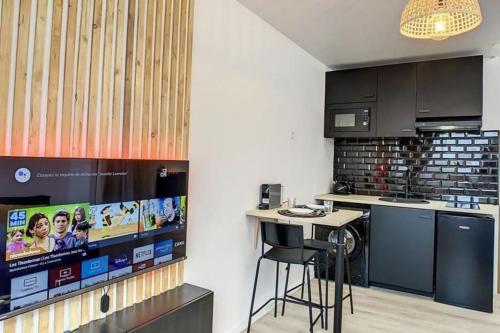 - une cuisine avec un bar et une télévision dans la chambre dans l'établissement L'Haneri - Center, WIFI - Comfort et Modern Style, à Amiens