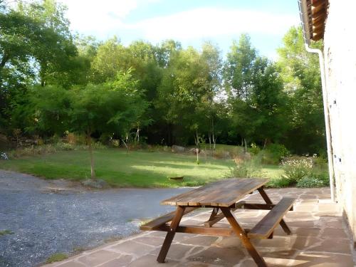 a wooden picnic table sitting on a patio at Domaine du Plan Del Poux Gite Rural in Combret