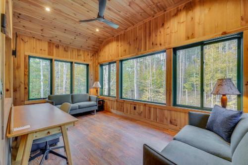 a living room with wood paneled walls and windows at Riverfront Hideaway in Keene Walk to Town! in Keene