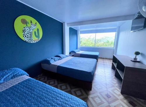 a blue room with two beds and a window at Hotel Zipa Villeta - Sede Campestre in Villeta