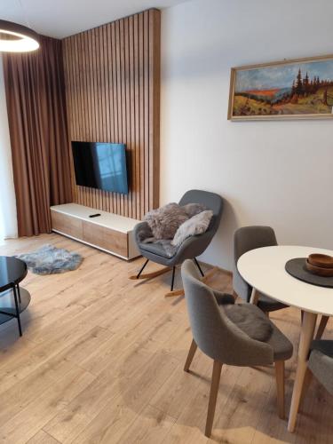 a living room with a table and chairs and a tv at Apartments Relax Tále in Evergreen Resort in Tale