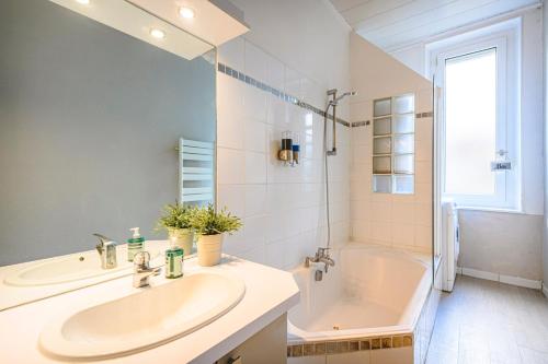 La salle de bains blanche est pourvue d'un lavabo et d'une baignoire. dans l'établissement Le Jardin Reims Cathedrale, à Reims