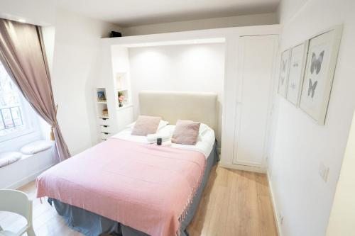 Cette petite chambre comprend un lit avec des draps roses. dans l'établissement Studio parisien face metro - Paris 9 - 2p - FLAT-GUEST, à Paris