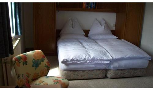 a bed with white sheets and a chair in a room at Haus Talblick in Bad Gastein