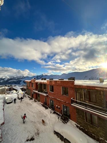 Una persona parada en la nieve frente a los edificios. en Cozy and Tiny Nest in Gudauri, en Gudauri