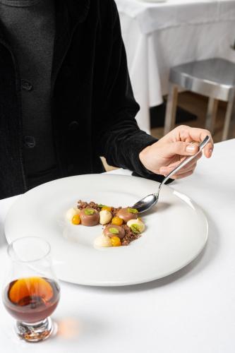 a person sitting at a table with a plate of food at Montana Lodge & Spa, by R Collection Hotels in La Thuile