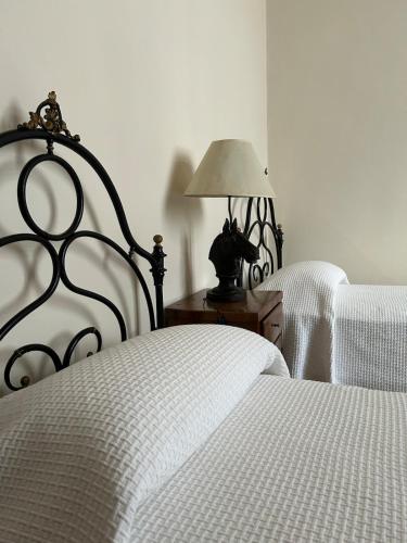 a bedroom with two beds with white sheets and a lamp at Barchessa di Villa Tiepolo Passi in Carbonera