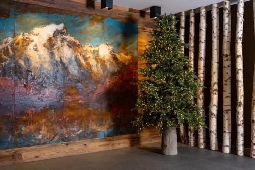 a christmas tree in front of a painting at Montana Lodge & Spa, by R Collection Hotels in La Thuile