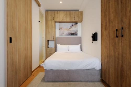 a bedroom with a white bed and wooden cabinets at Casa Colón by Wynwood House in Mexico City