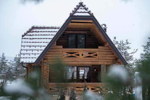 a log cabin in the woods with snow on the roof at Aurum Cabins in Zlatibor