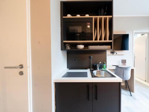 a kitchen with a sink and a microwave at JustStay Mülheim Hotel & Apartments in Mülheim an der Ruhr