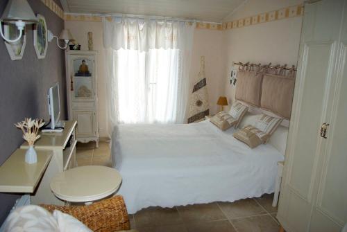 Un dormitorio con una gran cama blanca y una mesa en B&B Villa Viva Vitale, en Pierrevert