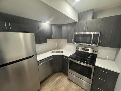 a kitchen with stainless steel appliances and wooden cabinets at 1-Bedroom - On site Parking - near YQR Airport in Regina