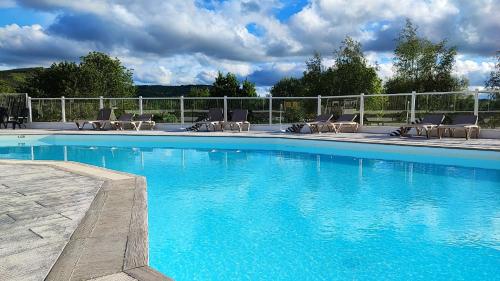 une piscine bleue avec des chaises et une clôture dans l'établissement Camping Rieumontagné, à Nages