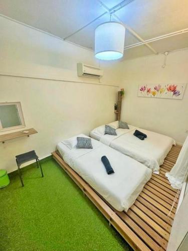 two beds in a room with a green carpet at Jonker Vibe Inn in Malacca