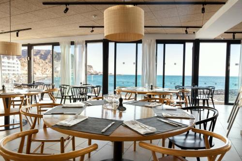 a restaurant with tables and chairs and a view of the ocean at Ocean Beach Club Gran Canaria in Mogán