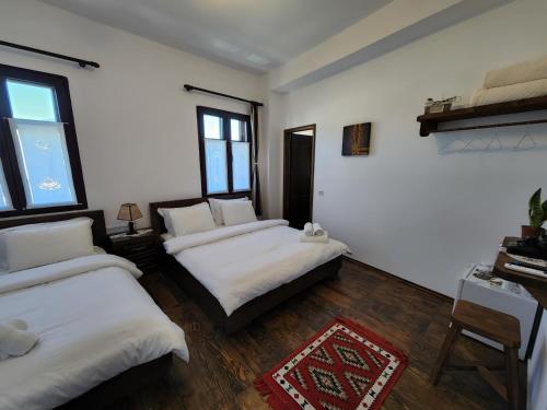 two beds in a room with white walls and wooden floors at Sokak Boutique Hotel in Berat
