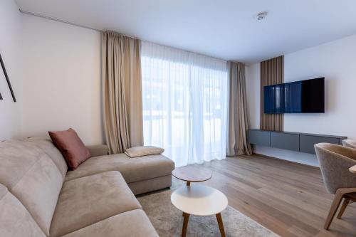 a living room with a couch and a tv at Alpine Suite Spot in Bad Mitterndorf