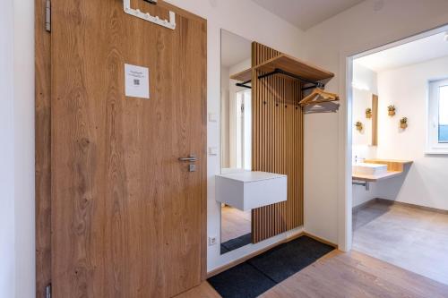 a hallway with a wooden door and a white sink at Alpine Suite Spot in Bad Mitterndorf