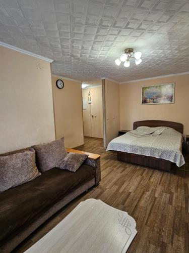 a living room with a couch and a bed at Lux Apartment on Potanina 19 in Ustʼ-Kamenogorsk