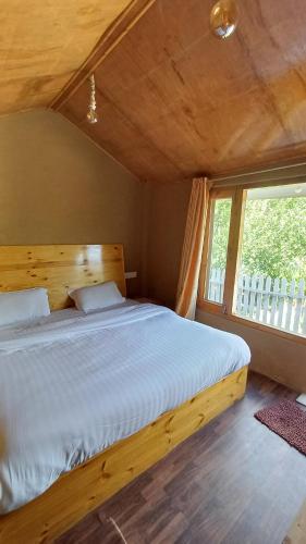 um quarto com uma cama grande e uma janela grande em Enthralling Escapes Nature Stay and Trek em Manali