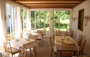 un comedor con mesas y sillas blancas y ventanas en Skorianzhof, en Eberndorf