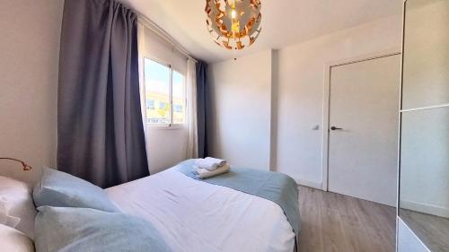 a bedroom with a bed and a window and a chandelier at Residencial Las Dunas, Best Holiday Home Resort On The Island- VV in Corralejo