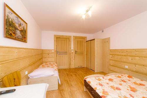 two beds in a room with wooden walls at Dom wczasowy Anna Maria in Sierockie