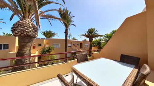 a table and chairs on a balcony with palm trees at Residencial Las Dunas, Best Holiday Home Resort On The Island- VV in Corralejo