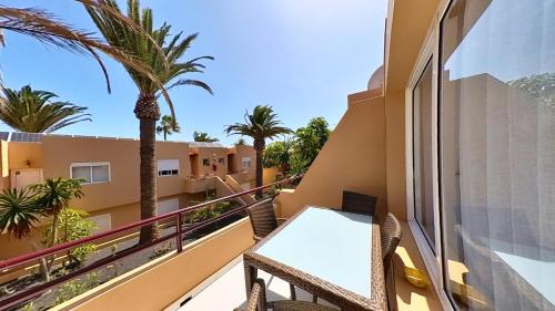 a balcony with a table and palm trees at Residencial Las Dunas, Best Holiday Home Resort On The Island- VV in Corralejo