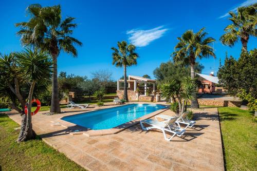 a swimming pool with palm trees and a house at Finca Linda in Campos