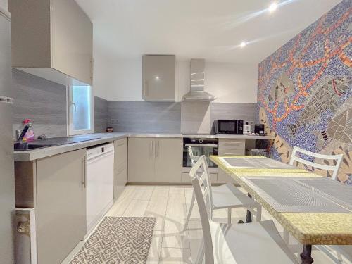 a kitchen with white cabinets and a table with chairs at Studio d'artiste climatisée, proche plage in Fréjus
