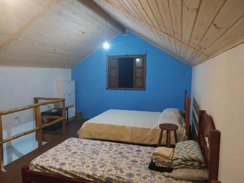 a bedroom with two beds and a blue wall at chale da naty 1 in Paraty