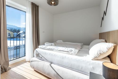 a white bedroom with a bed and a large window at Alpine Suite Spot in Bad Mitterndorf