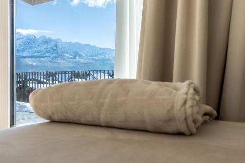 a pillow sitting on a bed in front of a window at Alpine Suite Spot in Bad Mitterndorf