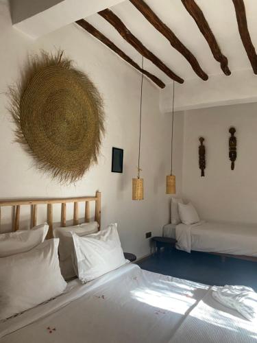 a bedroom with two beds and a basket on the wall at La Ferme Berbere Adult only in El Harkat