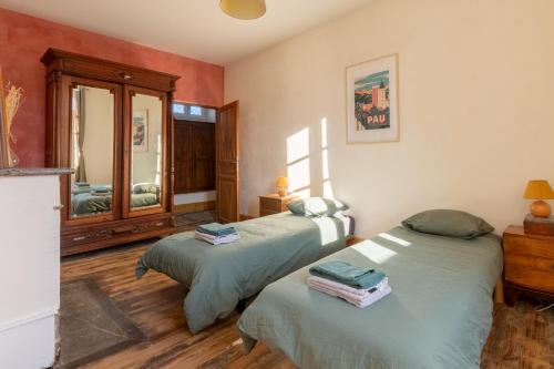 a bedroom with two beds and a mirror at La Maison Tonio in Ossun