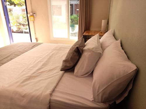 a large white bed with four pillows on it at Baan Nuk Anong in Chiang Rai