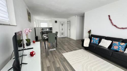 un soggiorno con un divano nero e un tavolo di Logement moderne au cœur de l'Alsace a Niederbronn