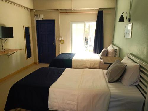 a hotel room with two beds and a window at Baan Nuk Anong in Chiang Rai