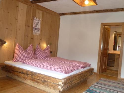 a bedroom with a bed with red pillows on it at Bauernhof im Wiesengrund in Maria Luggau