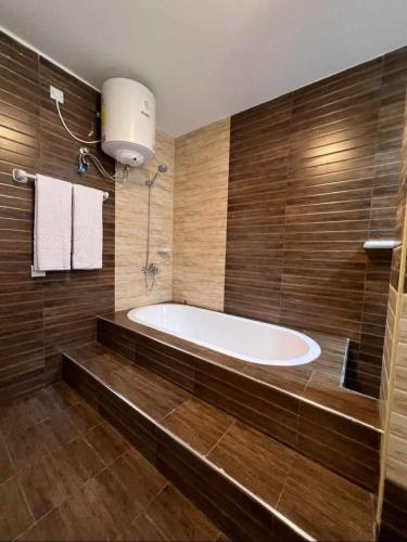 a bath tub in a bathroom with wooden walls at Grand Orchid Hotel Apartment in Duqm