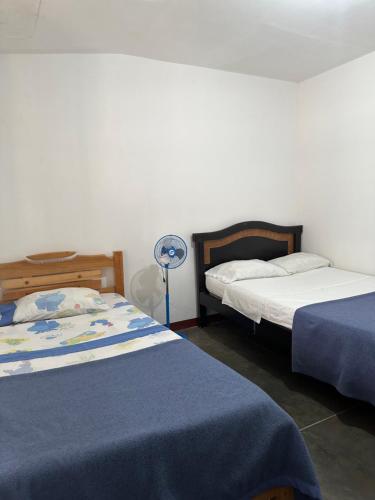 a bedroom with two beds and a fan at El Patriarca Hotel in Sasaima