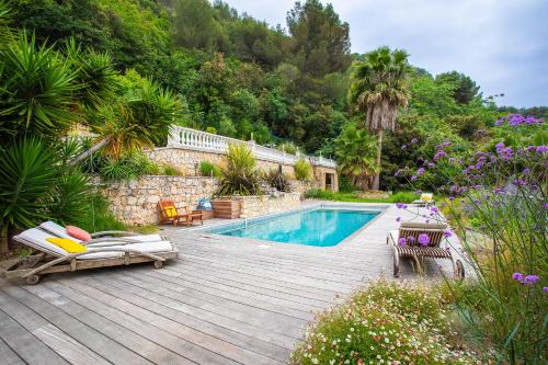 une cour arrière avec une piscine et une terrasse en bois dans l'établissement VILLA NIDAZUR VI4413 By Riviera Holiday Homes, à Nice