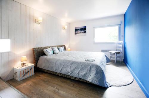 a bedroom with a bed and a blue wall at Villa Land-Zee, à 10mn de Royan in Saujon