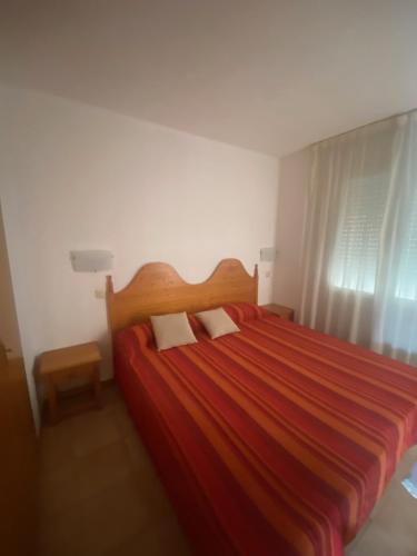 Un dormitorio con una cama roja con dos almohadas. en Gran Reserva 24, en Empuriabrava